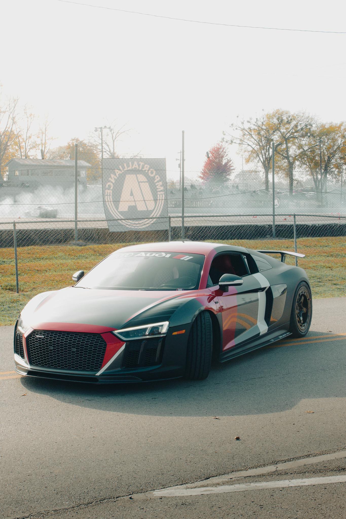 A sleek Audi R8 supercar parked on a race track with a vibrant design.
