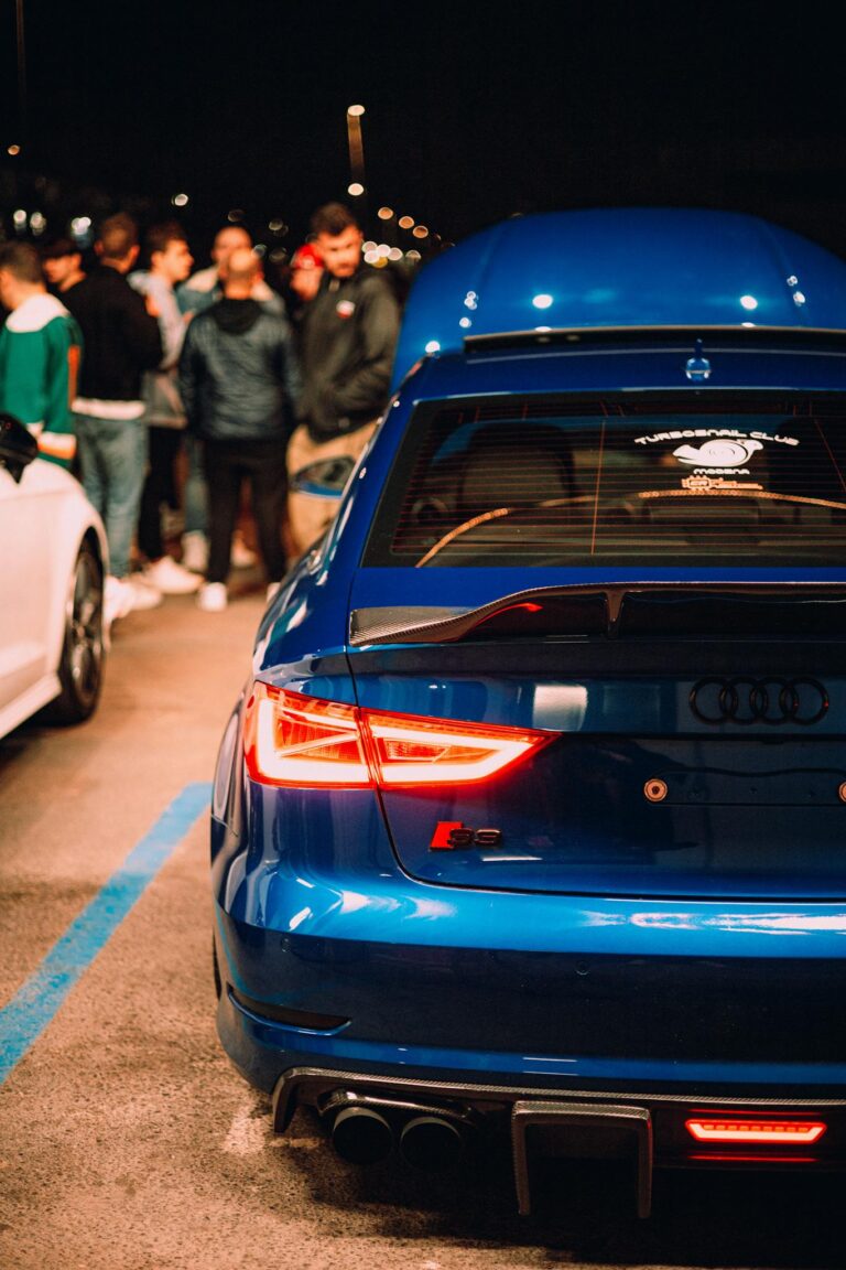 Vibrant nighttime car meet showcasing a blue Audi RS with a group of people.